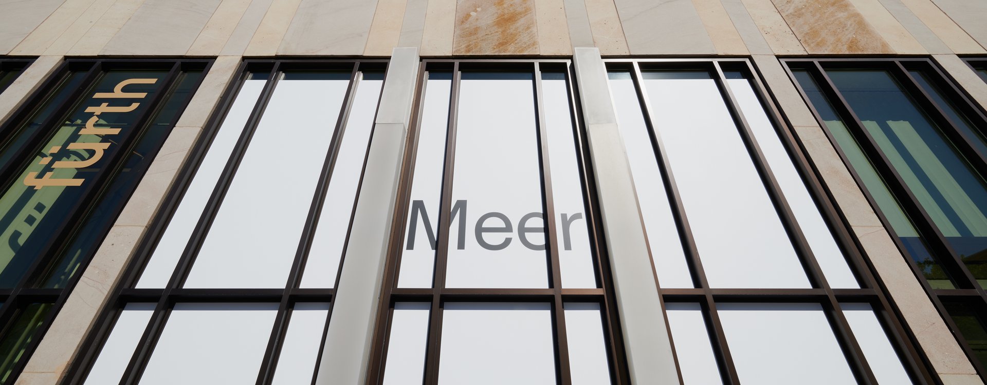 Fassade der Kunstgalerie mit vertikalen Fenstern und dem Schriftzug 'Meer'