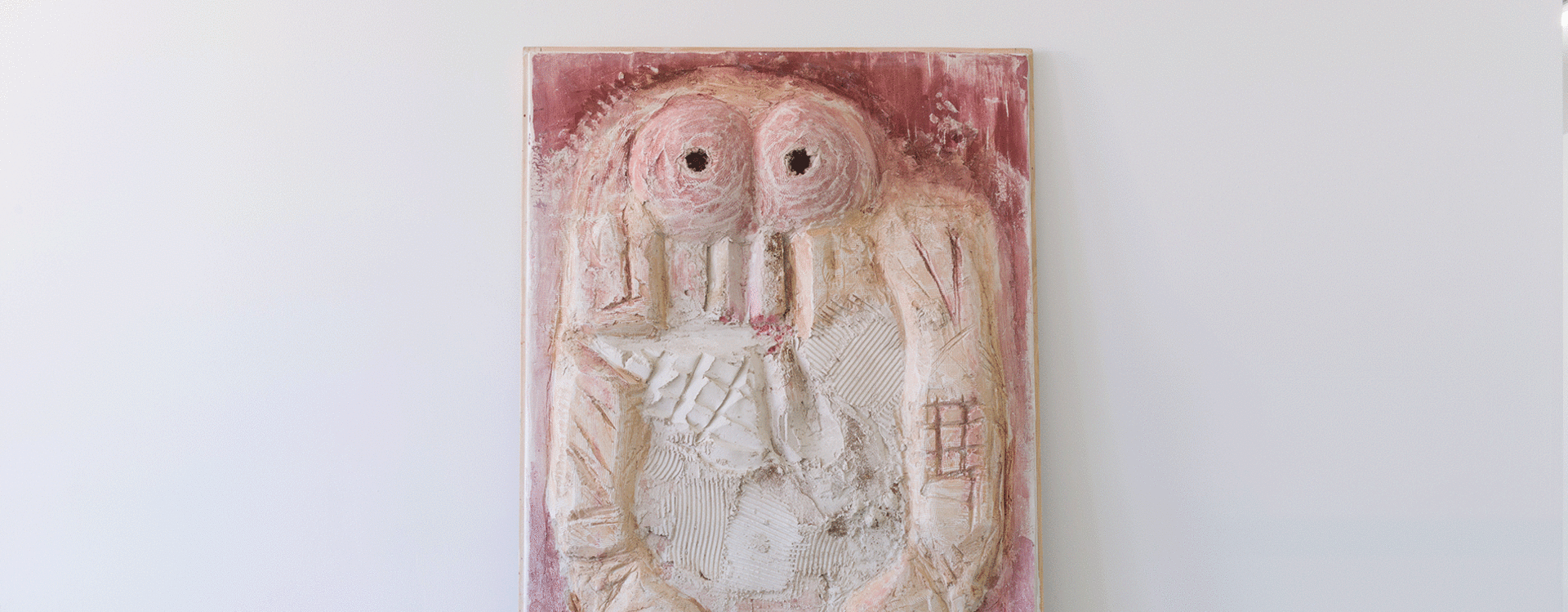 Relief mit abstrakter, symmetrischer Figur mit zwei großen Augen auf einem rechteckigen, rosa-weißen Hintergrund
