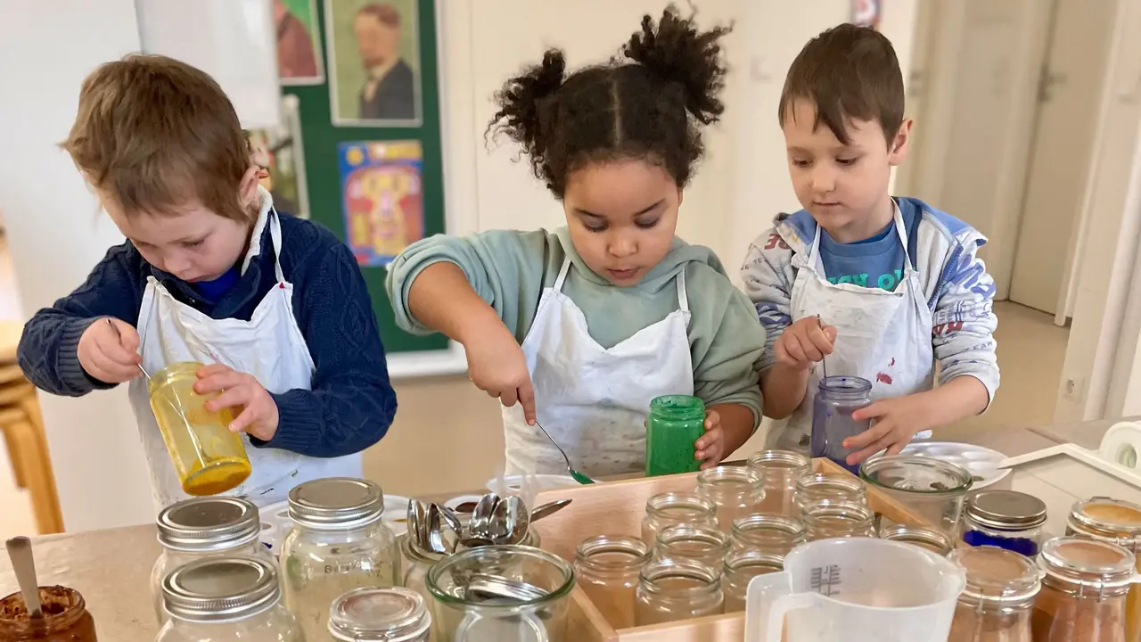 Drei Kinder experimentieren mit Farbpigmenten