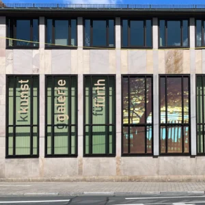 Fassade der Kunstgalerie mit großen Fenstern, in denen die Wörter 'kunst galerie fürth' vertikal angeordnet sind. In zwei Fenstern ist eine Fotografie zu sehen.