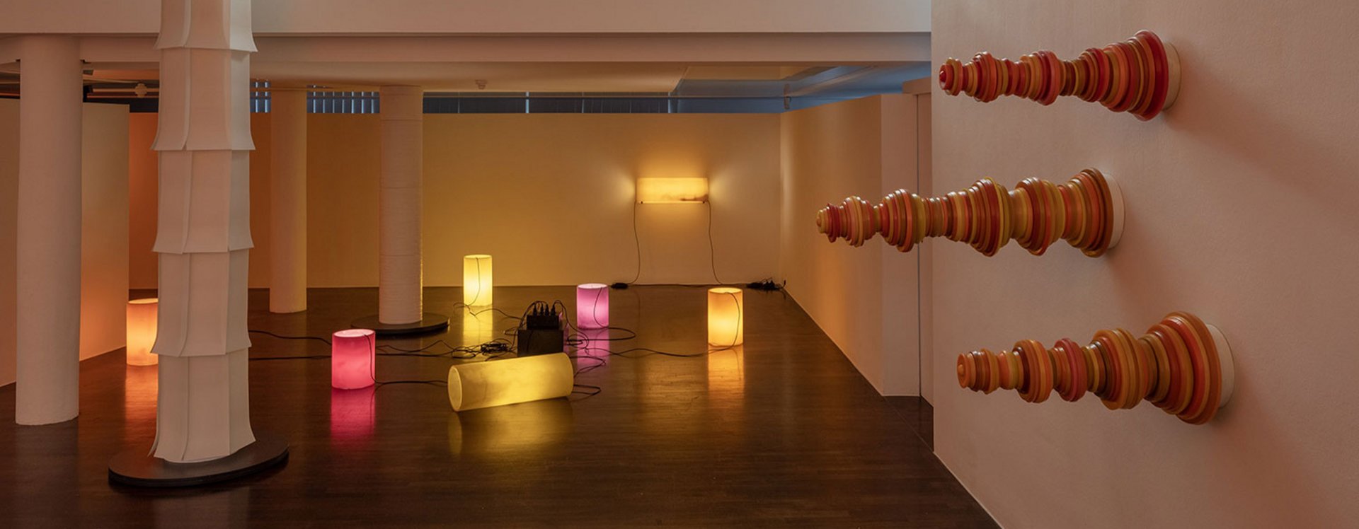 Blick in die Ausstellung mit iluminierten Objekten und Schachfiguren, die horizontal an die Wand montiert sind.