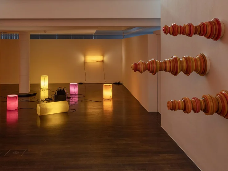 Blick in die Ausstellung mit iluminierten Objekten und Schachfiguren, die horizontal an die Wand montiert sind.