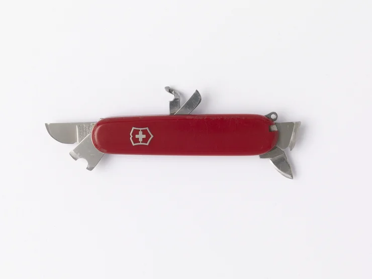 Rotes Schweizer Taschenmesser mit mehreren ausgeklappten Werkzeugen auf weißem Hintergrund